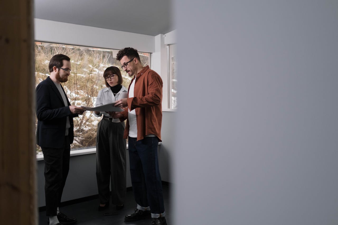 Three adults discussing a project inside a well-lit modern office setting.